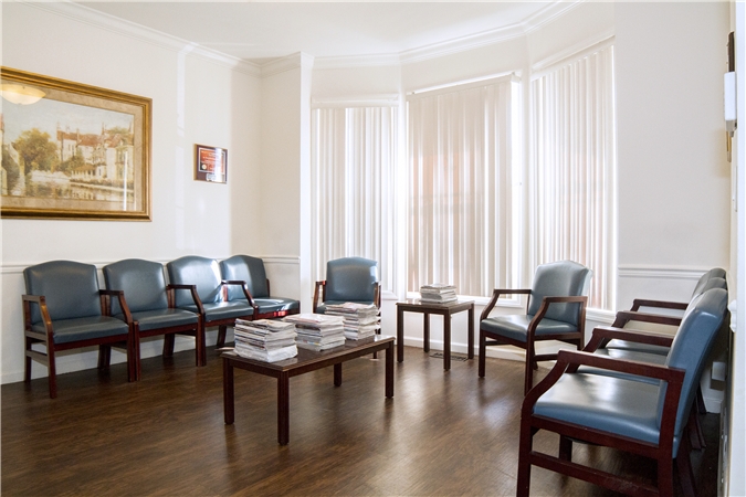 Photo of our waiting room: chairs by bay windows and dark hardwood flooring